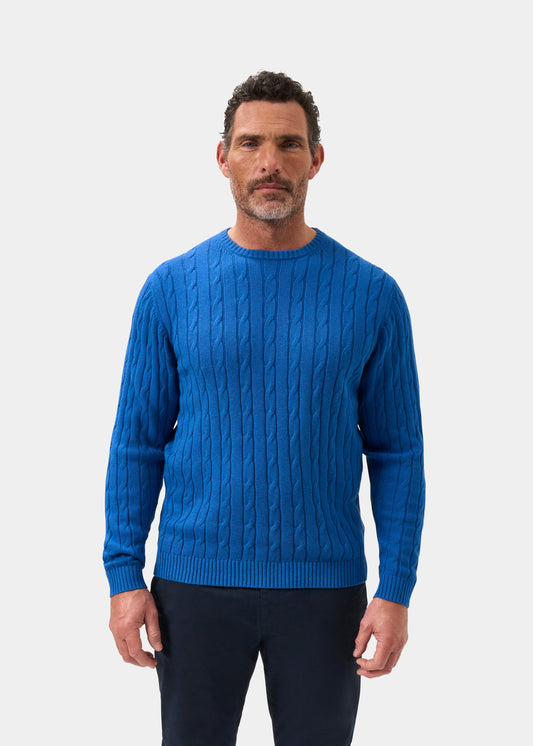 Man in Honley Regatta blue cotton cashmere cable jumper (regular fit) and dark pants stands against a white background.