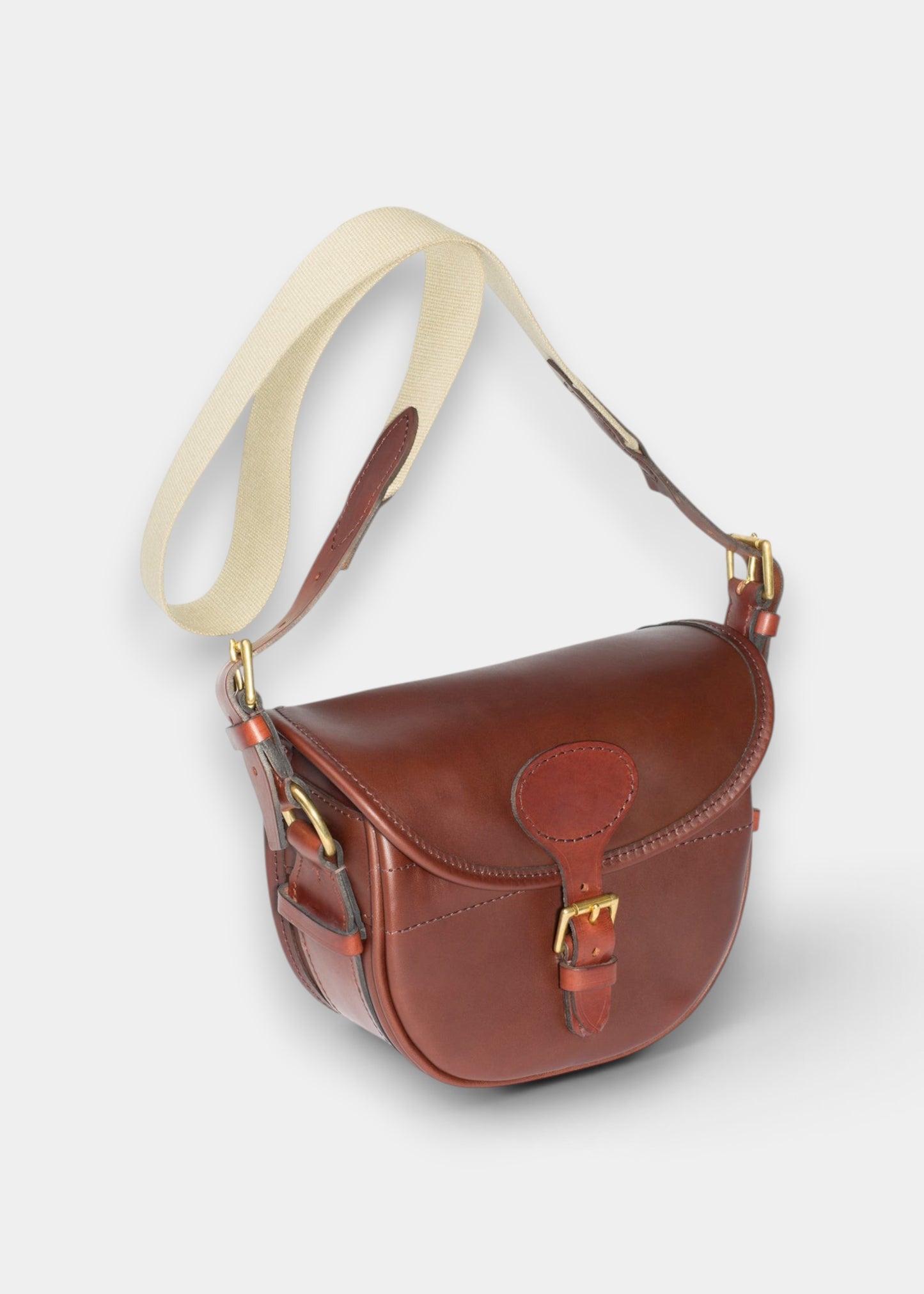 Alan Paine brown harness leather cartridge bag with antique brass fittings and a cream canvas shoulder strap