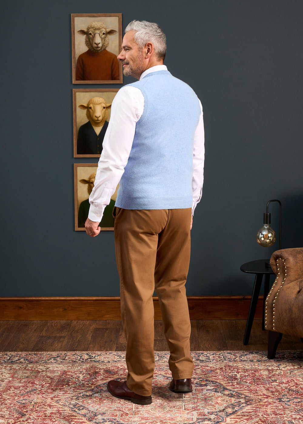 A man seen from behind wearing a Norfolk Lambswool V-Neck Slipover In Glacier over a white shirt and tan trousers.