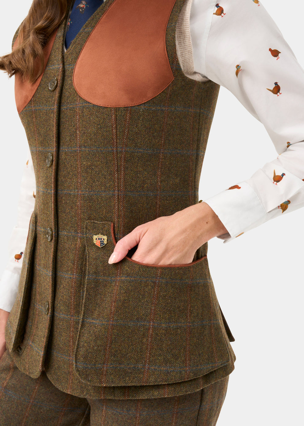 Woman in a Combrook Ladies Willow Tweed Shooting Waistcoat and pants, white bird print shirt, leather patches.