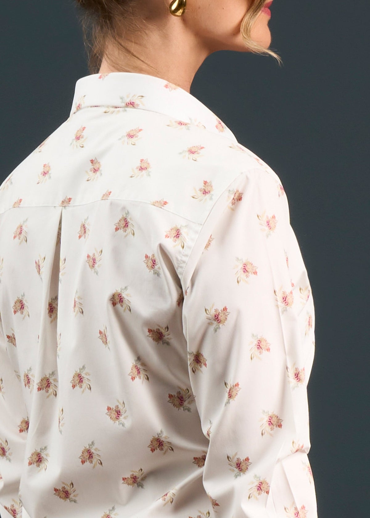 Woman wearing the Lawen Cotton Printed Shirt in floral print with gold earrings, side view on gray background.