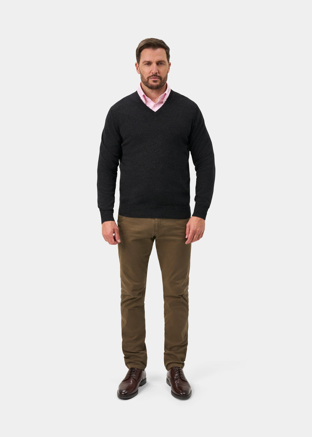 Man in a Haddington Pure Cashmere V-Neck Jumper in charcoal, pink shirt, brown pants, and shoes on white background.