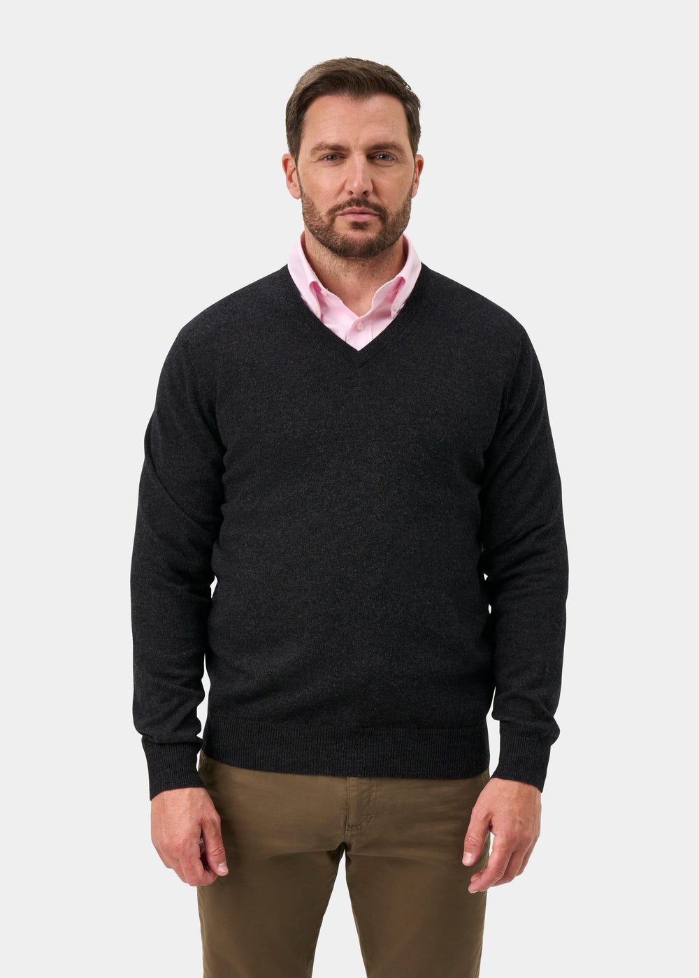 Man in Haddington Pure Cashmere V-Neck Jumper in charcoal, over a pink shirt and khakis, against a plain background.