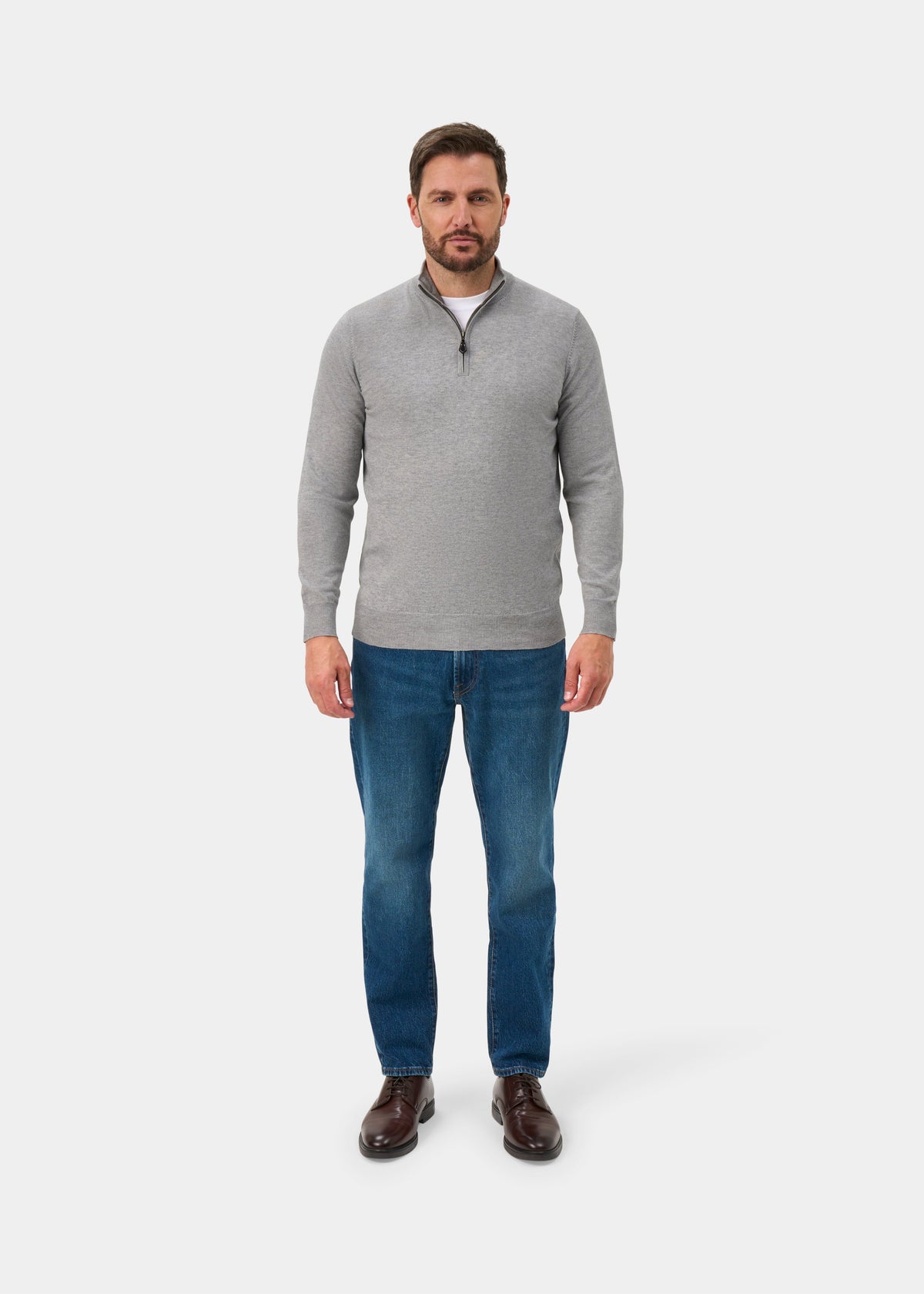 Man wears Ashfield Cotton Merino Quarter Zip Jumper in Light Grey Mix, blue jeans, and brown shoes on white background.