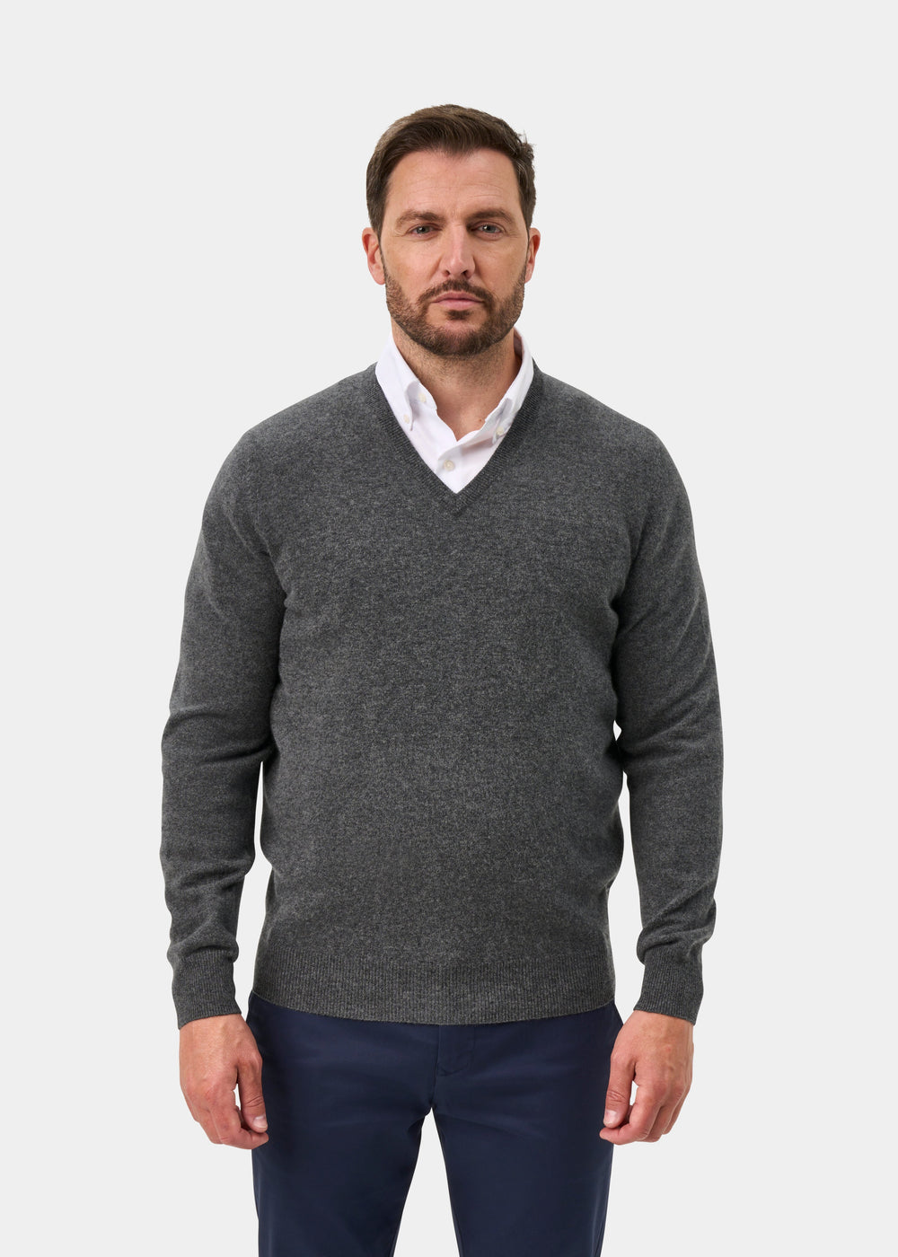 Man in an Albury Geelong Wool V-Neck Jumper in Derby, layered over a white shirt, on a plain white backdrop.