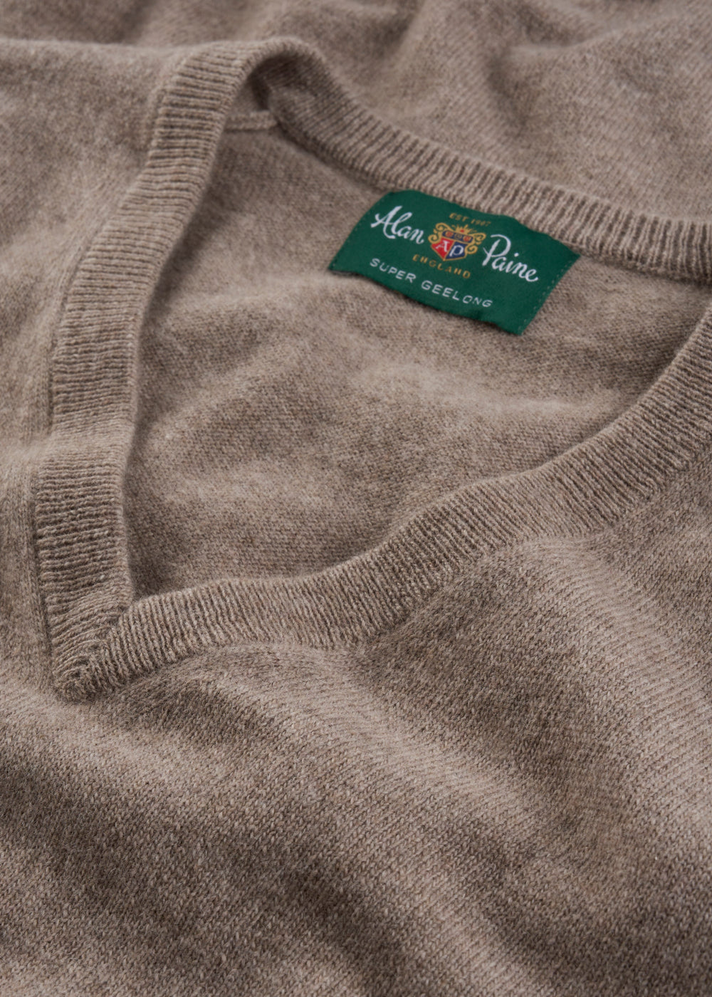 Close-up of Albury Geelong Wool V-Neck Jumper in Mushroom, highlighting texture and tag.