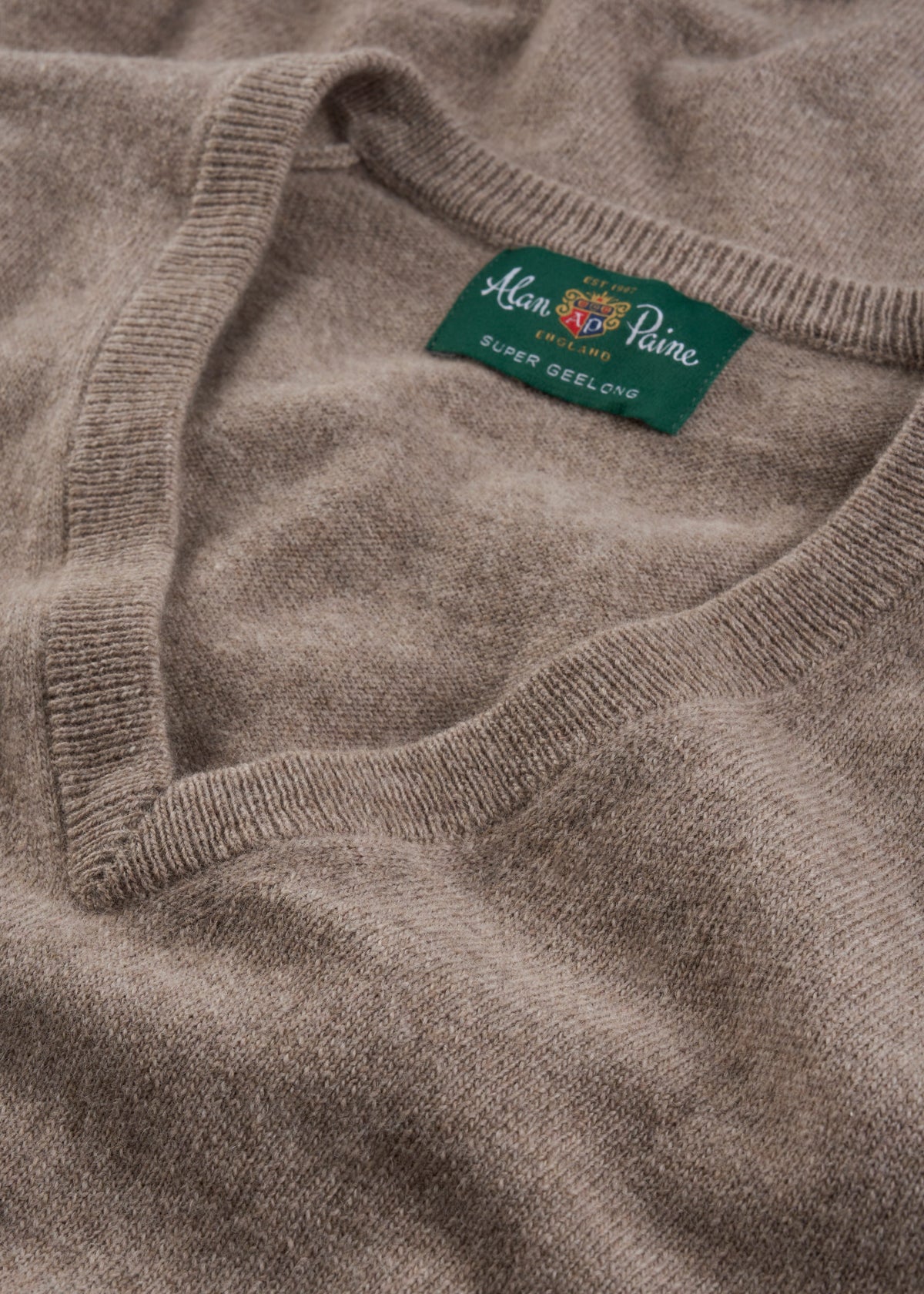 Close-up of Albury Geelong Wool V-Neck Jumper in Mushroom, highlighting texture and tag.