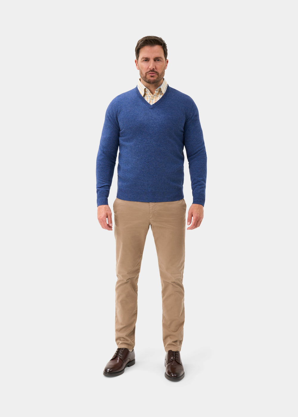 Man in an Albury Geelong Wool V-Neck Jumper in Ullswater, tan pants, brown shoes stands facing forward on white.