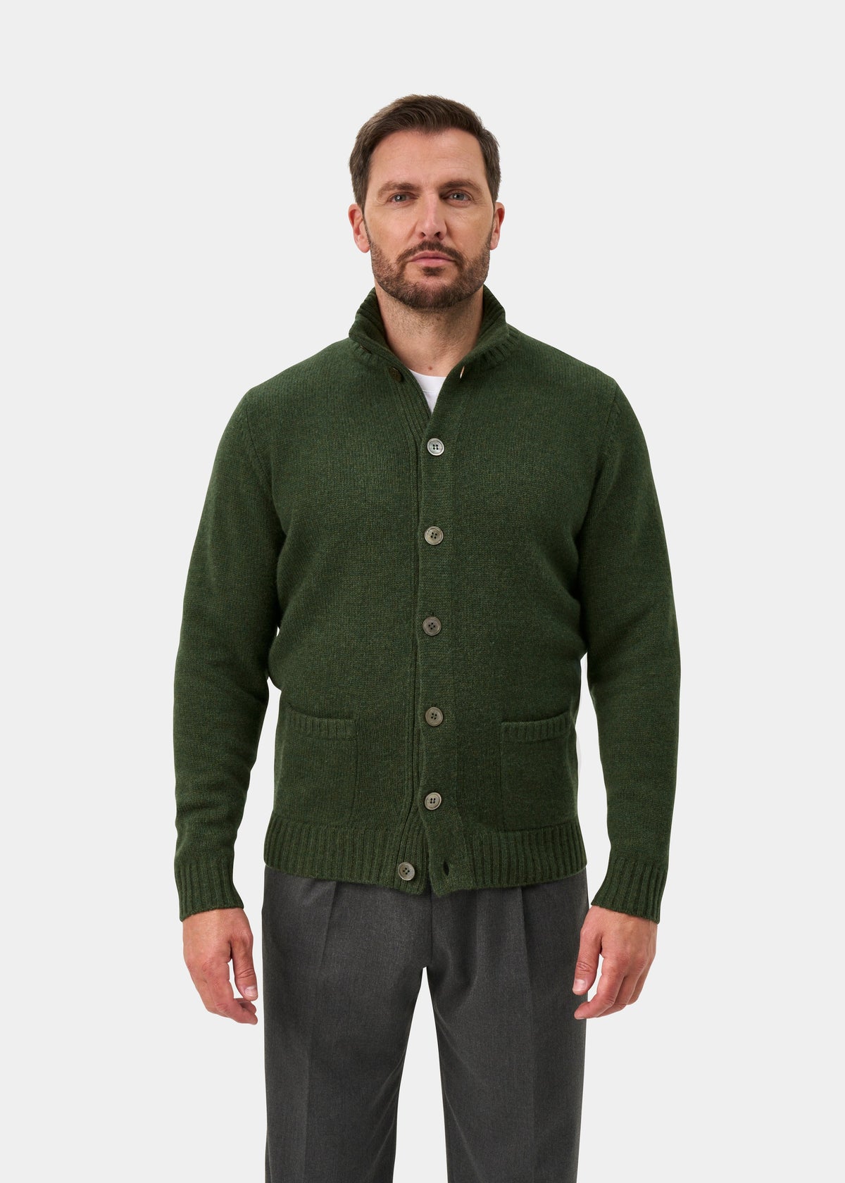 Man wears Landford Rosemary lambswool mock neck jumper over a white shirt and gray pants, against a plain background.