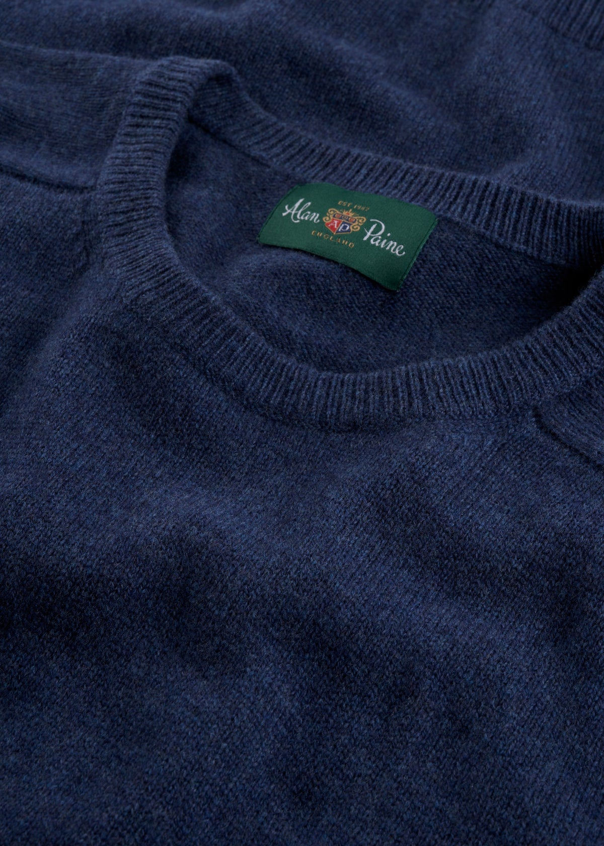 Close-up of the Lenzie Lambswool Crew Neck Jumper in Rhapsody, featuring a green Alan Paine label on the collar.