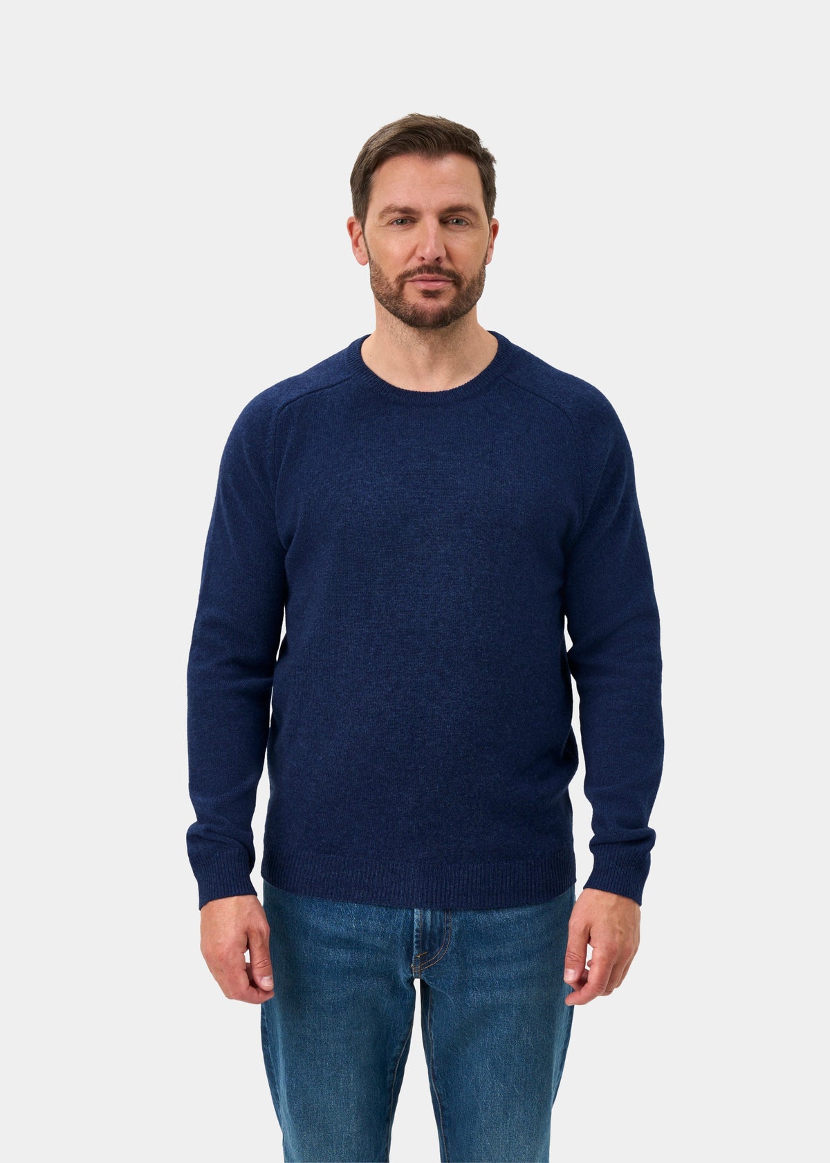 Man wears Lenzie Lambswool Crew Neck Jumper in Rhapsody (Regular Fit) with jeans, facing forward on white backdrop.