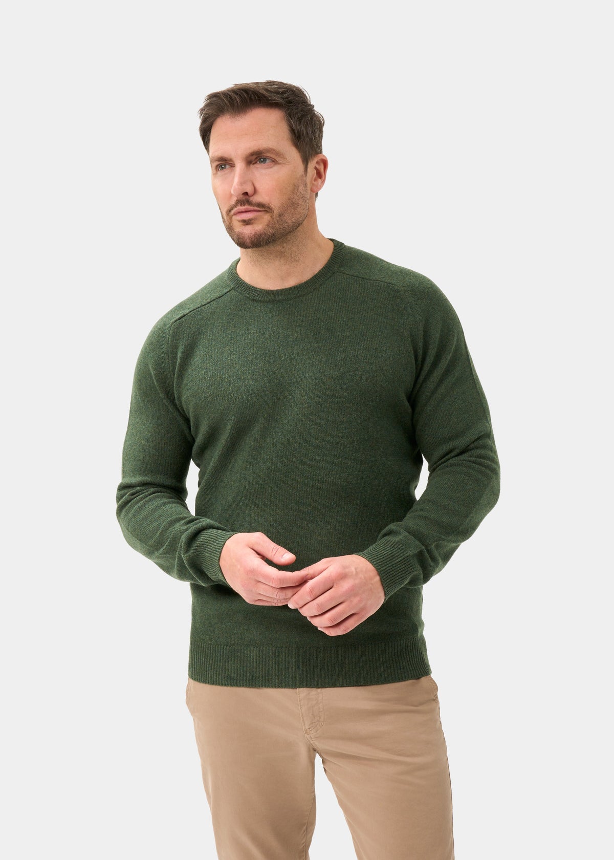 Man wears a Dorset Lambswool Crew Neck Jumper in Rosemary, classic fit, with tan pants against a plain background.