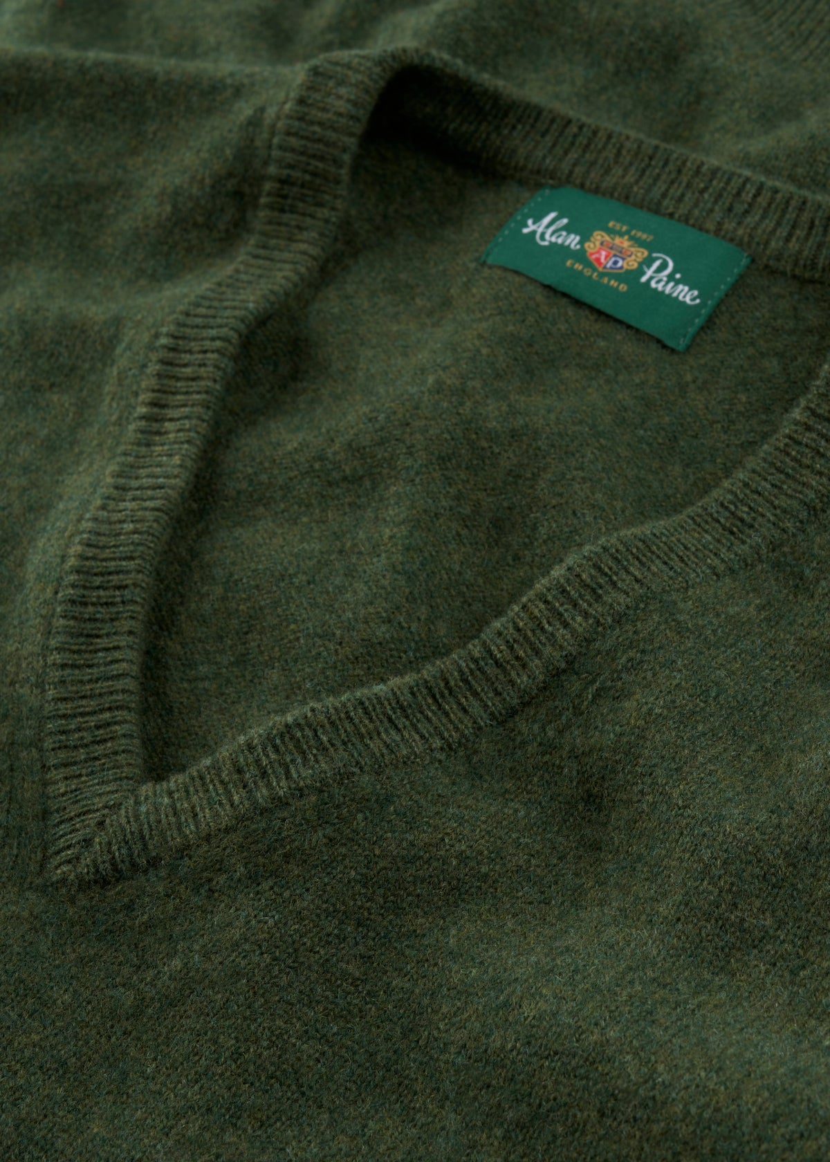 Norfolk Lambswool V-Neck Slipover in Rosemary, a soft dark green V-neck sweater with a ribbed collar and interior label.