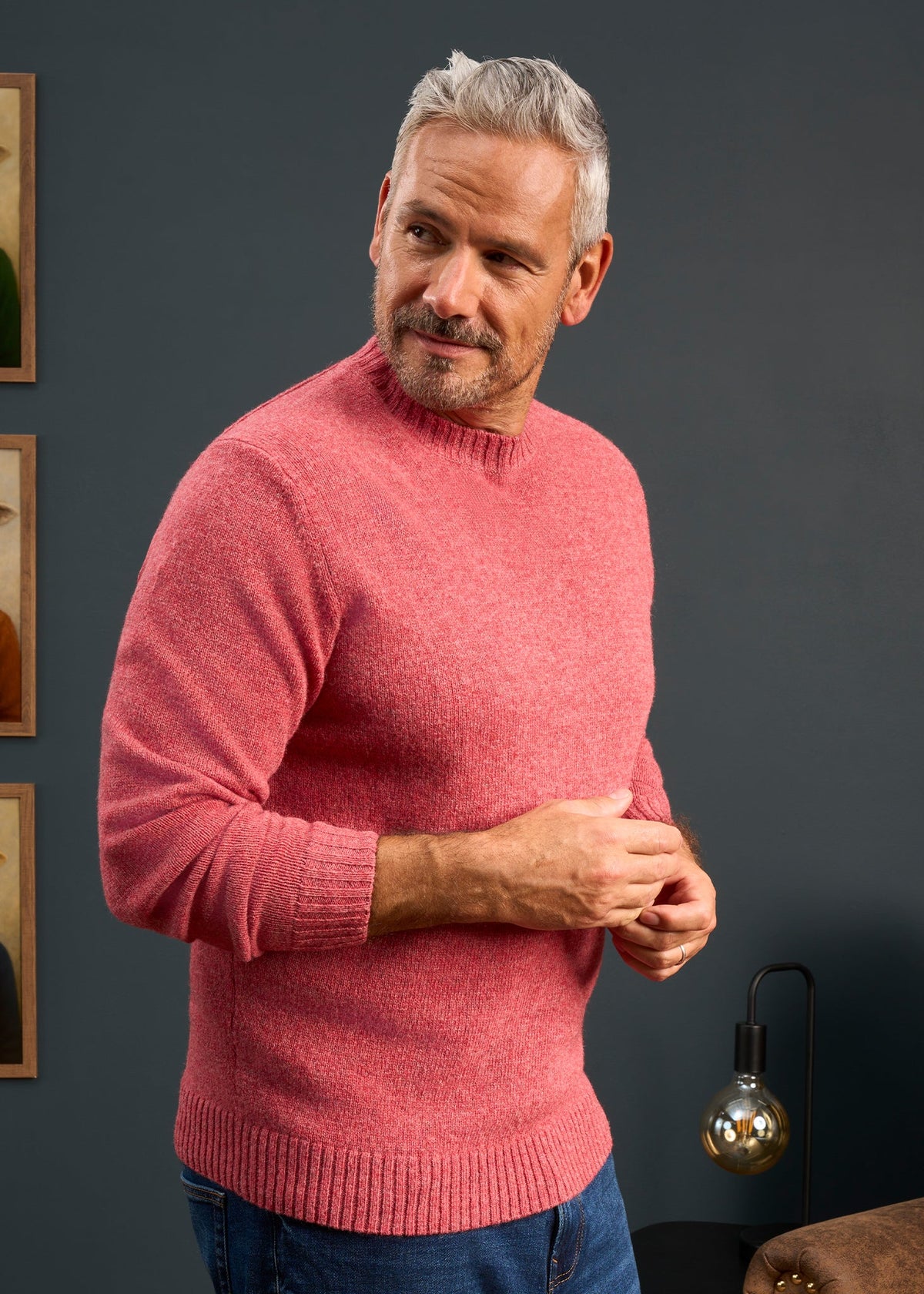 Man with gray hair and beard wears Kinnadie Supersoft Shetland Wool Crew Neck Jumper in Red Clover, looking sideways.