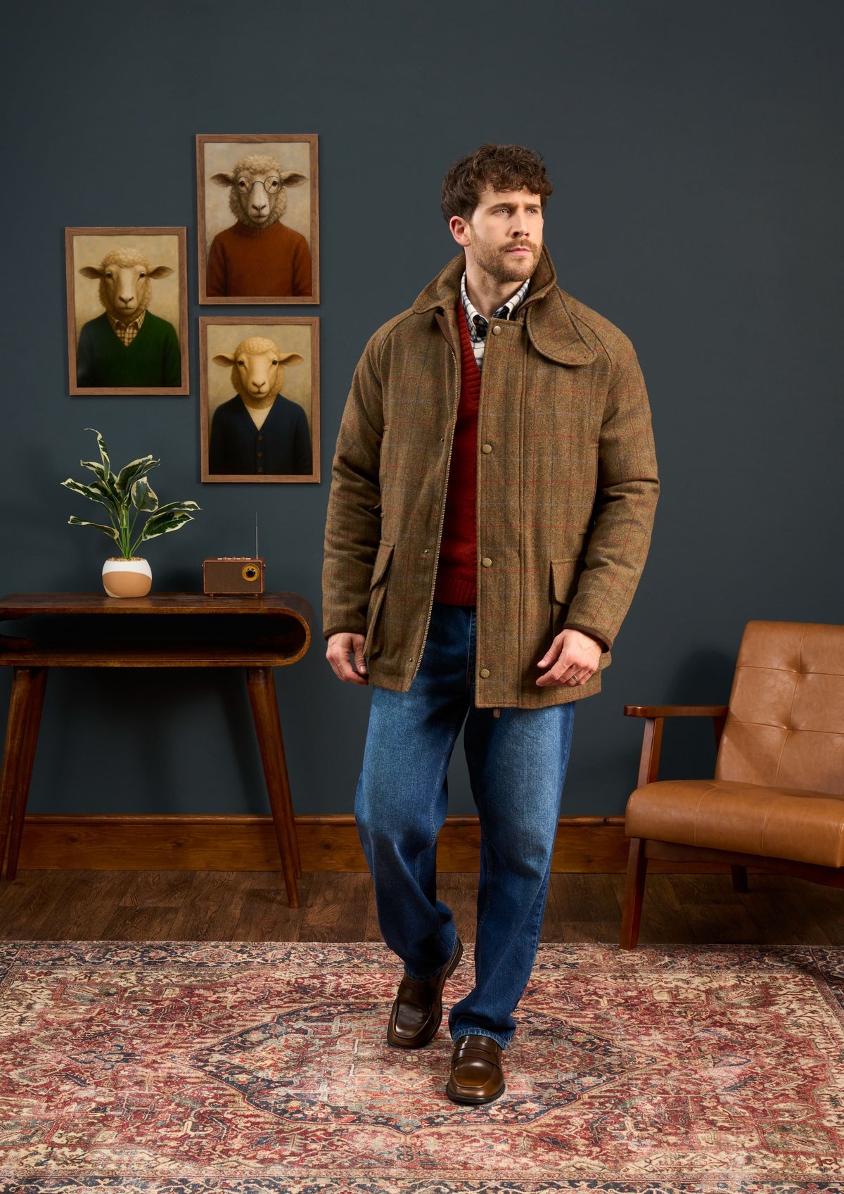 A man in casual wear stands in a stylish room, wearing the Surrey Men’s Tweed Waterproof Coat in Hawkswood - Shooting Fit.