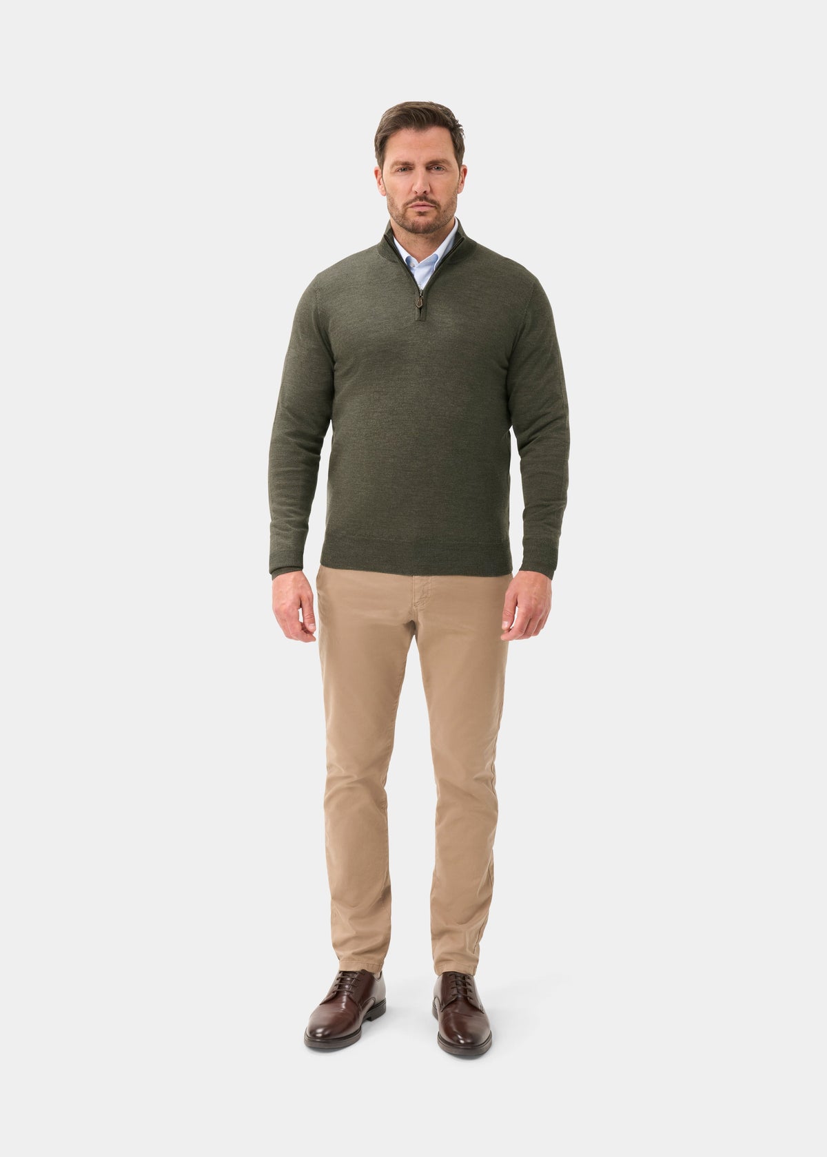 Man wears Barton Merino Wool Quarter Zip Jumper in Seaweed, khaki pants, and brown shoes against a white background.