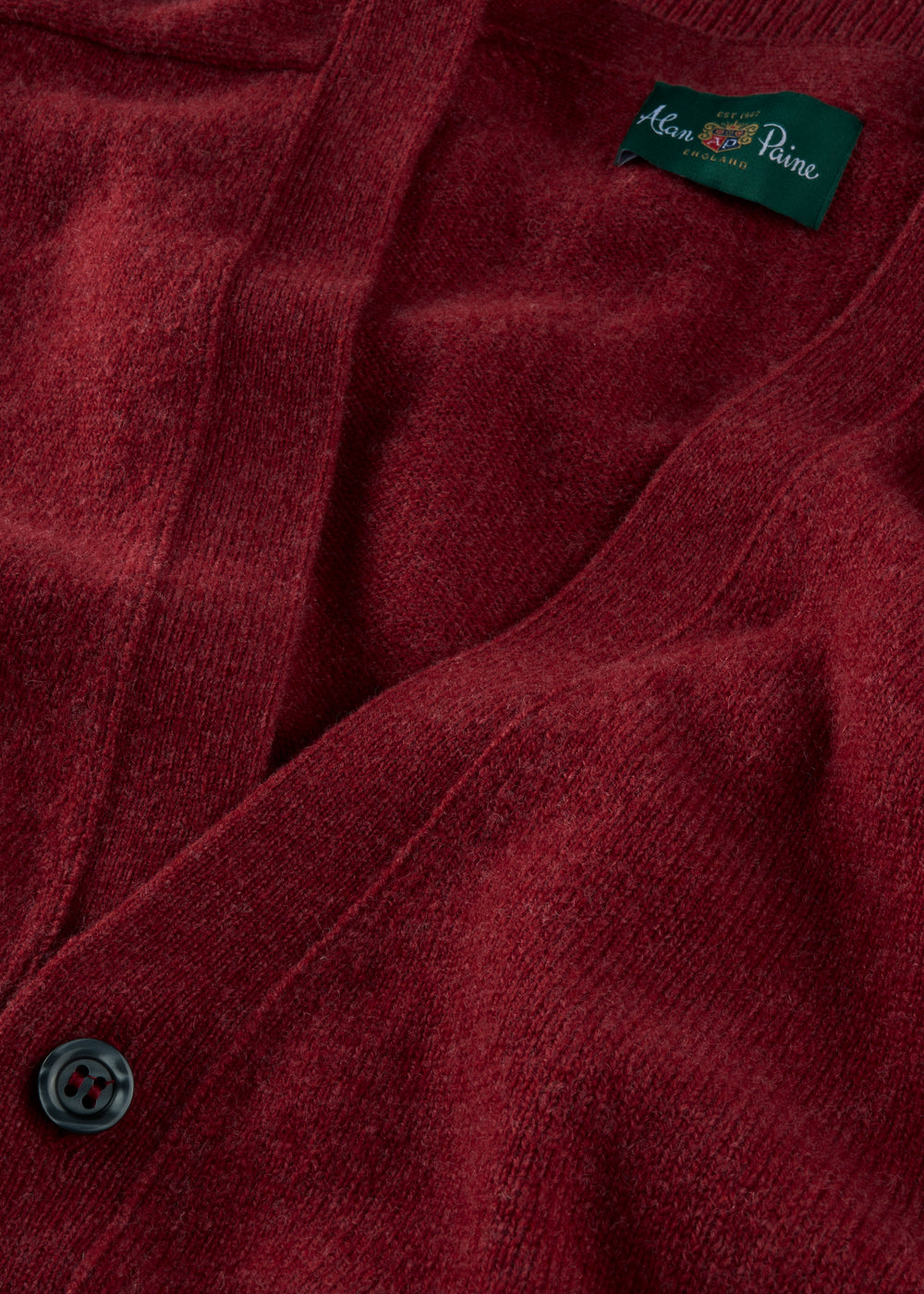 Close-up of a poppy red cardigan with a brand label