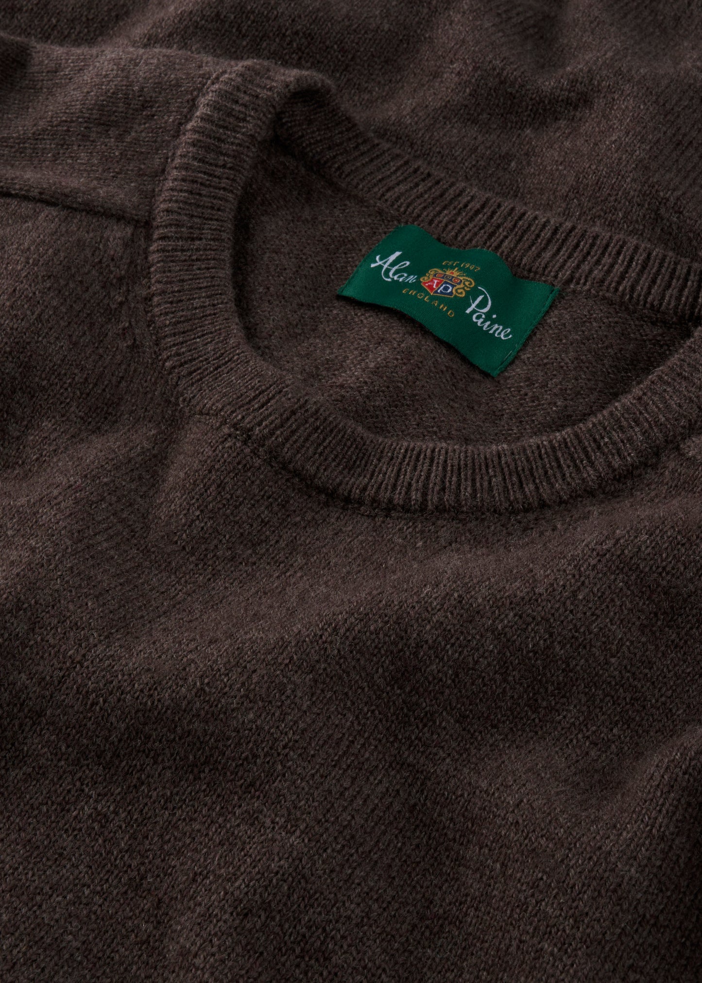 Close-up of a brown sweater with a brand label on the collar.