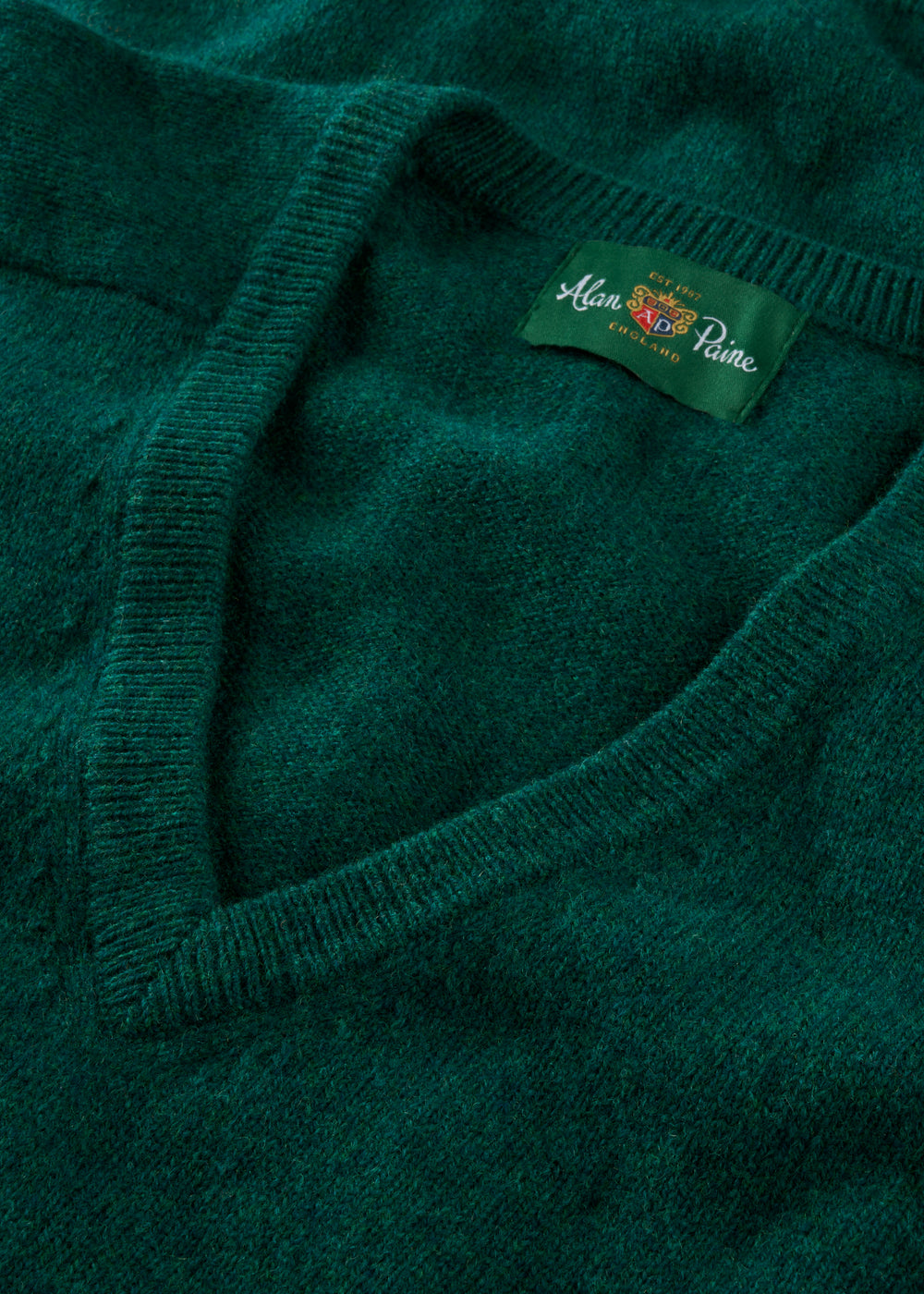 Close-up of a green sweater with a brand label on a matching green background