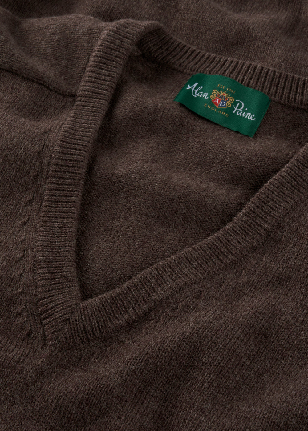 Close-up of a brown sweater with a brand label on the collar.