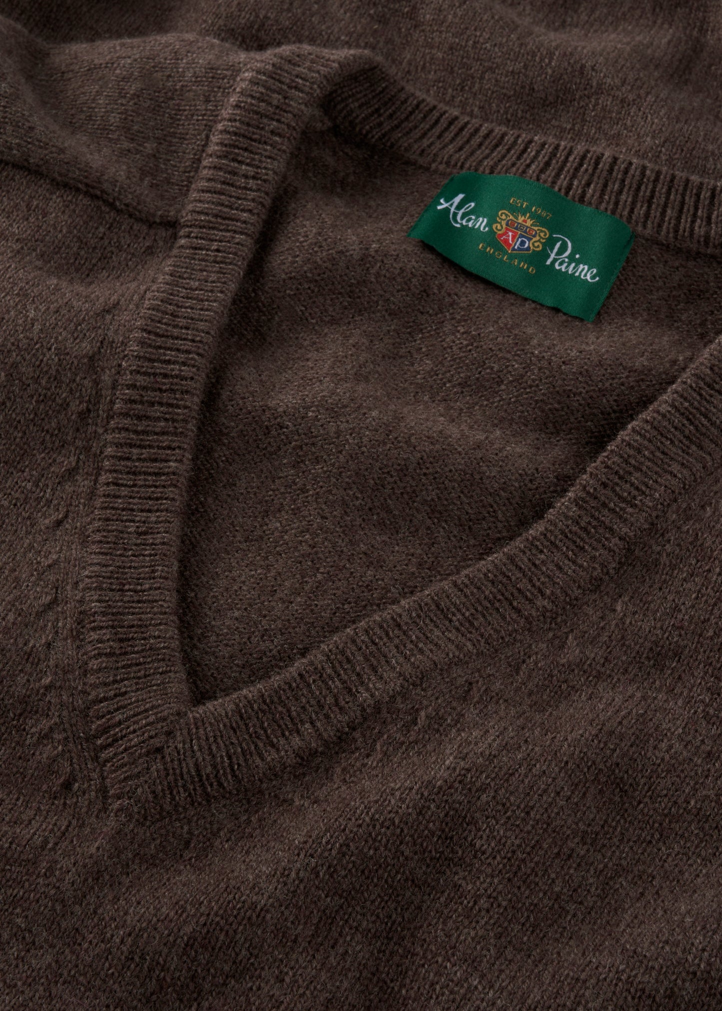 Close-up of a brown sweater with a brand label on the collar.