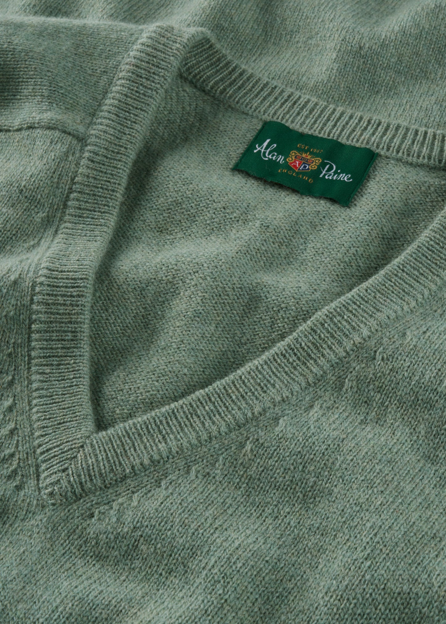 Close-up of a green sweater with a brand label on a matching background