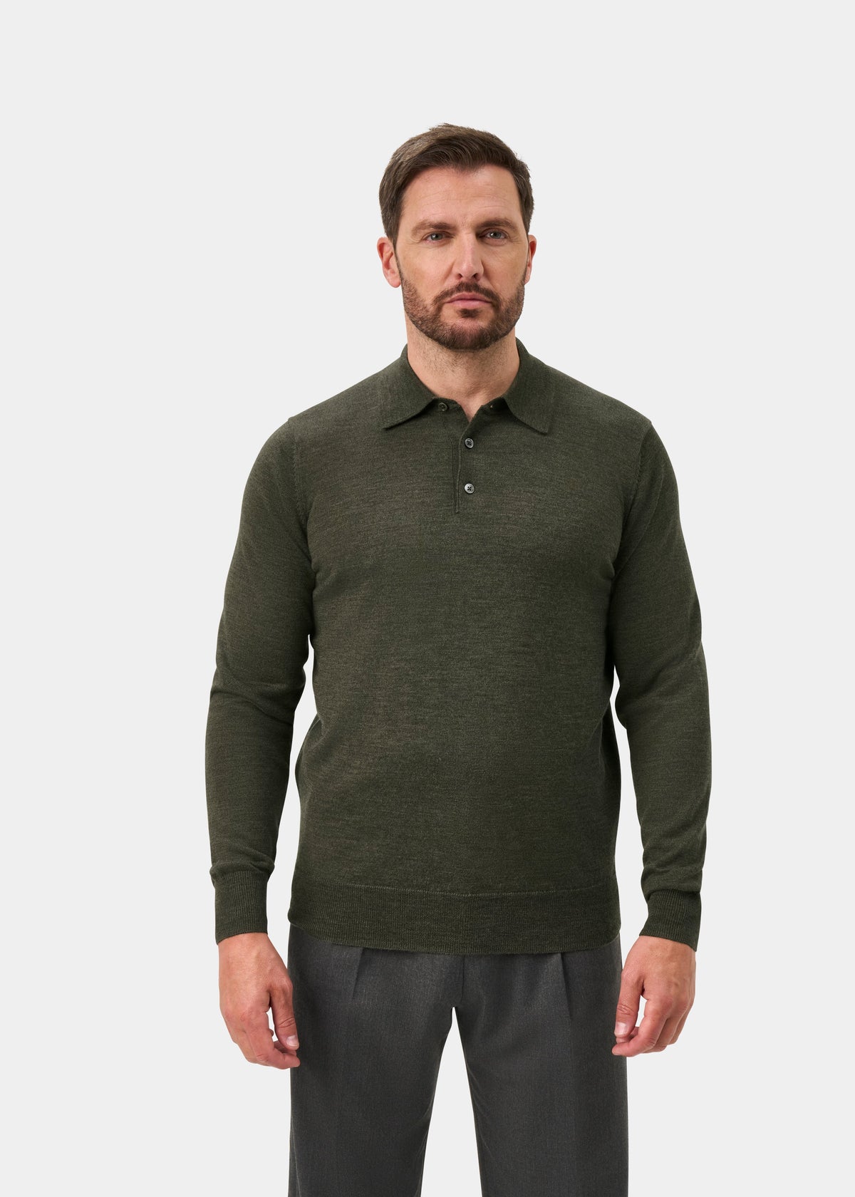 Man wears Hindhead Men’s Merino Wool Polo in Seaweed, regular fit, with gray pants against a plain white background.