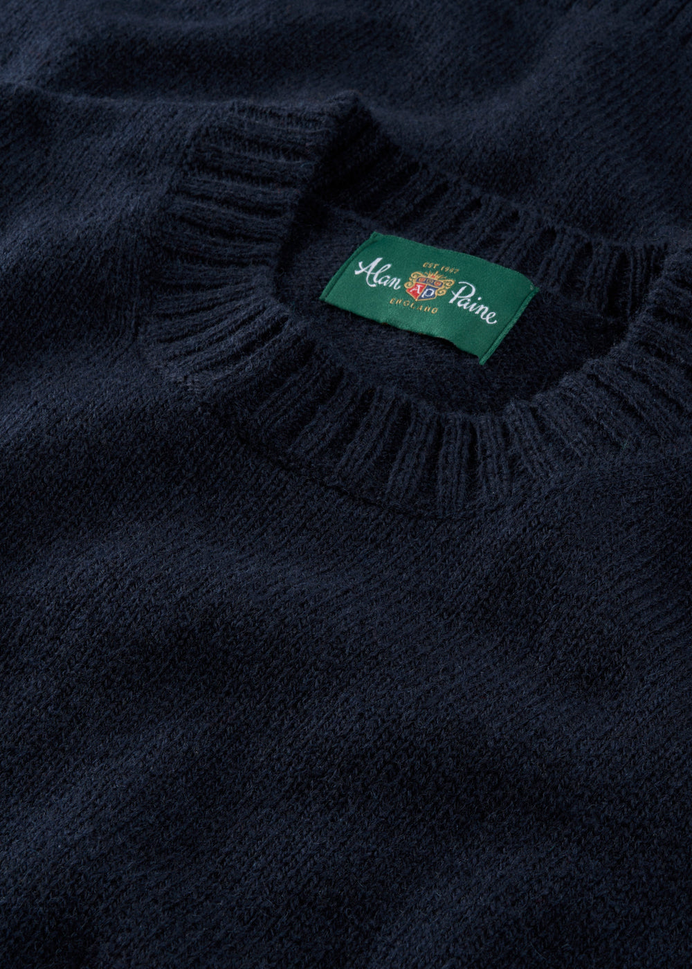 Close-up of the Kinnadie Supersoft Shetland Wool Crew Neck Jumper in Concord with ribbed collar and green label.
