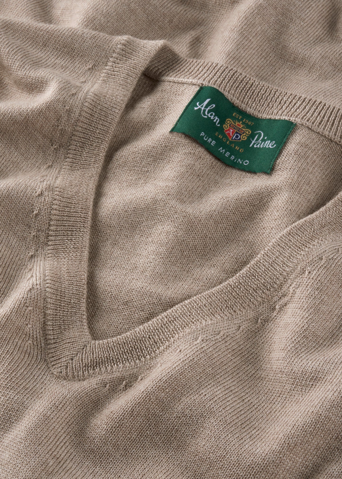 Close-up of a beige sweater with a brand label on the collar.