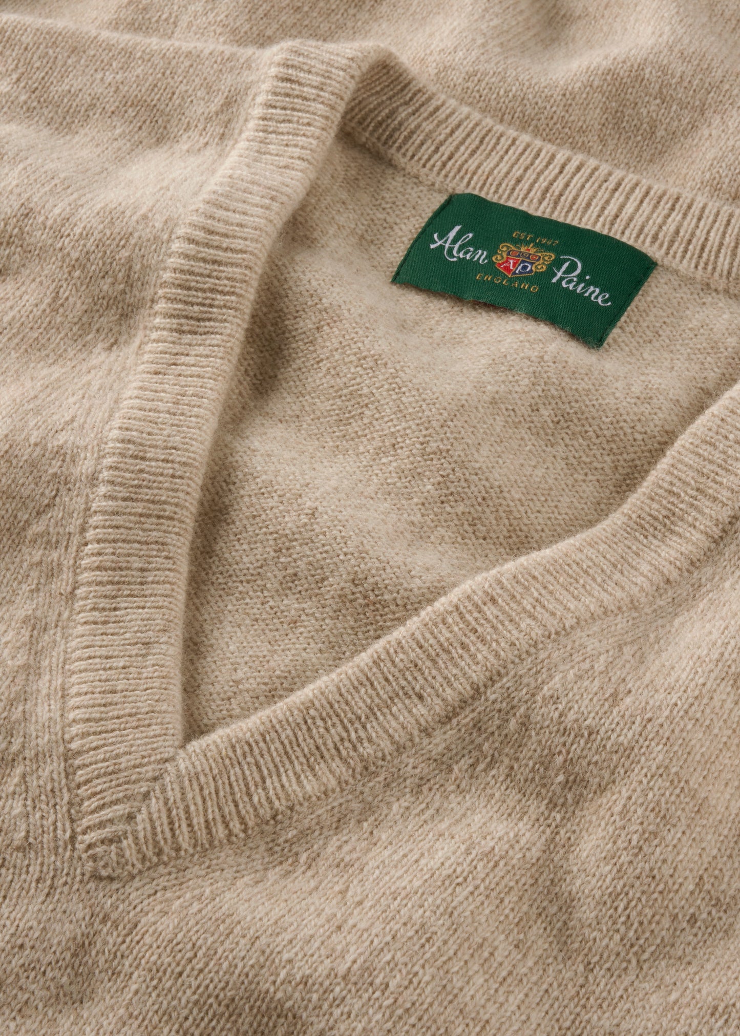Close-up of a beige sweater with a brand label on the collar.