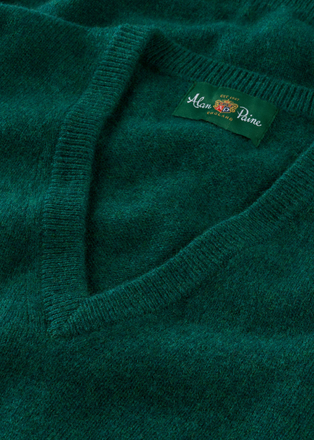 Close-up of a green sweater with a brand label on a matching background